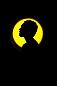 Creative silhouette portrait of a man in front of a vibrant yellow circle, artistic and striking in style.